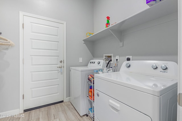 laundry room with washing machine and dryer and light hardwood / wood-style flooring