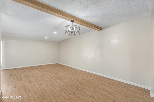 unfurnished room with beamed ceiling, light hardwood / wood-style flooring, a chandelier, and a textured ceiling