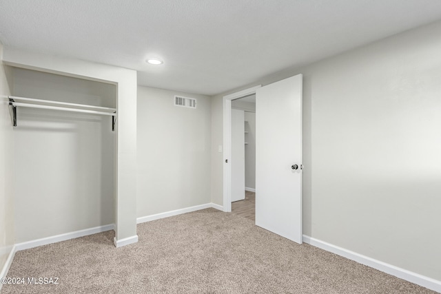 unfurnished bedroom featuring light carpet and a closet