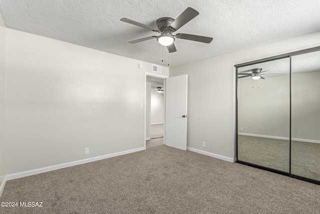 unfurnished bedroom featuring ceiling fan, a textured ceiling, a closet, and carpet