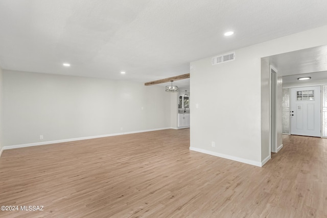 empty room featuring a textured ceiling and light hardwood / wood-style flooring