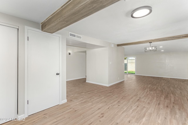 unfurnished room with light hardwood / wood-style flooring and beam ceiling