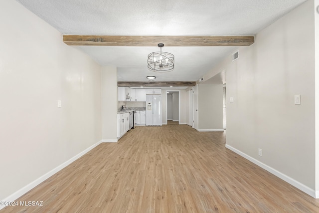 unfurnished living room featuring light hardwood / wood-style floors, beam ceiling, an inviting chandelier, and a textured ceiling