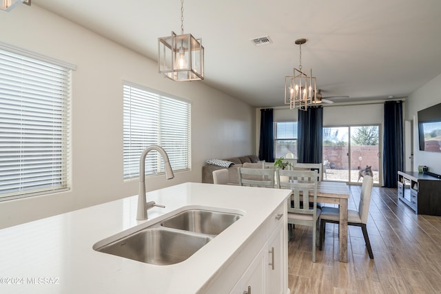 kitchen with sink, white cabinetry, pendant lighting, and hardwood / wood-style flooring