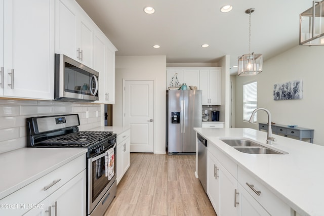 kitchen featuring pendant lighting, sink, white cabinets, and stainless steel appliances