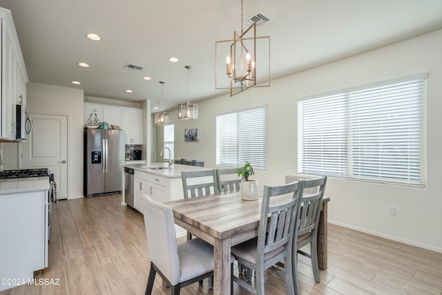 dining area with light hardwood / wood-style floors, a notable chandelier, and sink