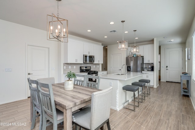 dining room featuring sink, light hardwood / wood-style flooring, and a chandelier