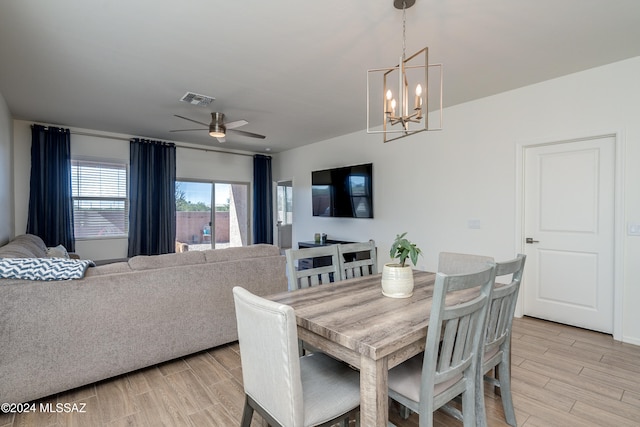 dining space with ceiling fan with notable chandelier and light hardwood / wood-style floors