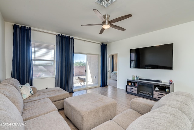 living room with ceiling fan, light hardwood / wood-style flooring, and a fireplace