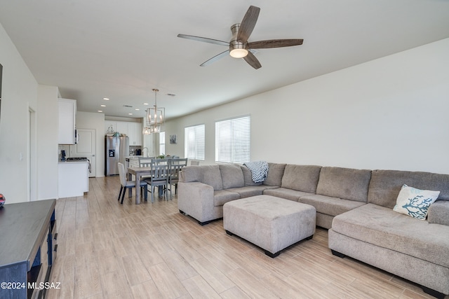 living room featuring light hardwood / wood-style flooring, sink, and ceiling fan with notable chandelier