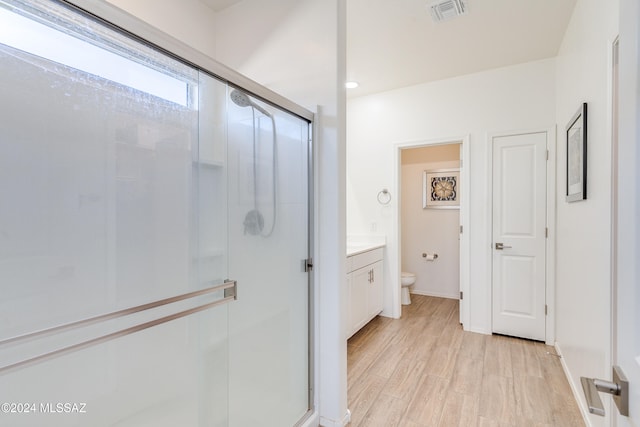 bathroom featuring vanity, toilet, wood-type flooring, and an enclosed shower