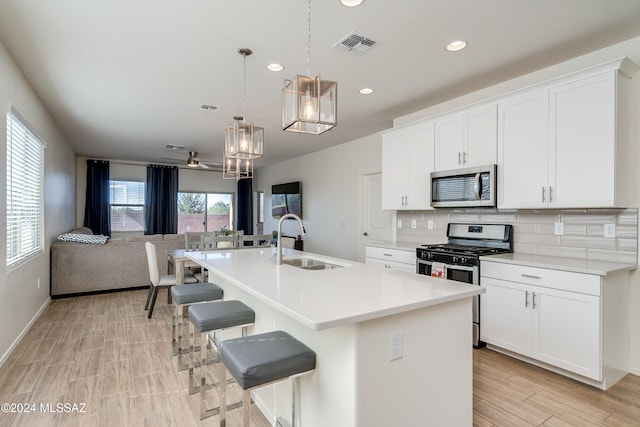 kitchen featuring white cabinets, an island with sink, sink, pendant lighting, and stainless steel appliances