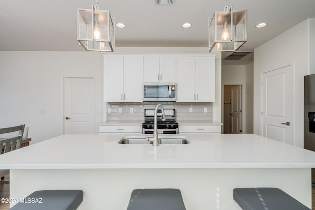 kitchen featuring white cabinets, a kitchen bar, sink, pendant lighting, and stainless steel appliances