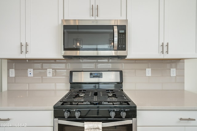 kitchen with decorative backsplash, white cabinets, and stainless steel appliances