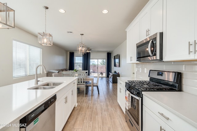 kitchen featuring sink, appliances with stainless steel finishes, decorative light fixtures, and white cabinetry