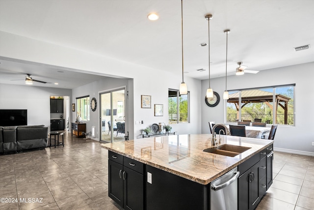 kitchen with a center island with sink, light stone countertops, dishwasher, sink, and decorative light fixtures