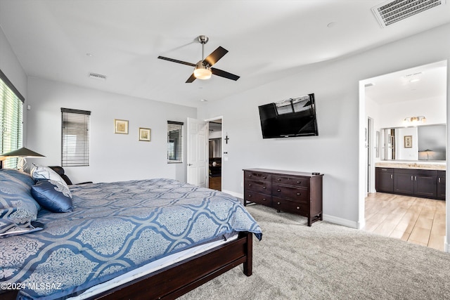 bedroom featuring connected bathroom, light wood-type flooring, and ceiling fan