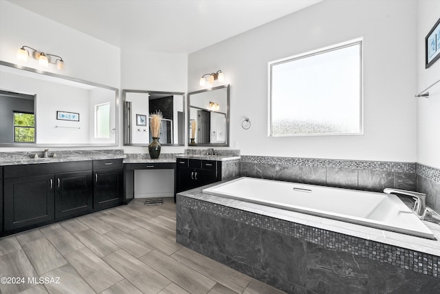 bathroom with vanity and tiled tub