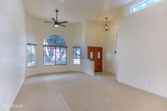 interior space featuring a healthy amount of sunlight, light colored carpet, and a towering ceiling