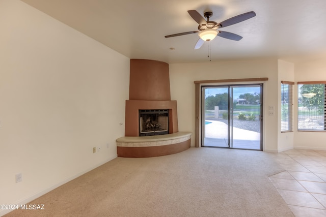 unfurnished living room featuring a large fireplace, light carpet, and ceiling fan