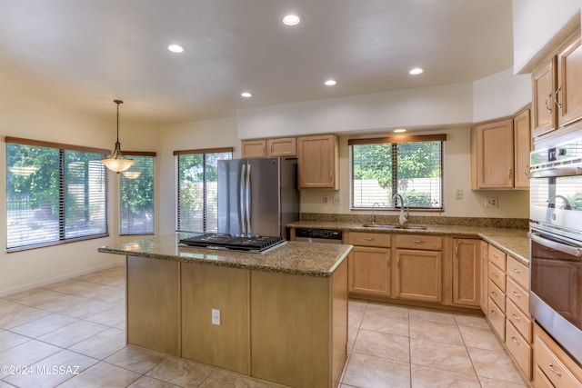 kitchen with hanging light fixtures, a kitchen island, stone counters, sink, and stainless steel appliances