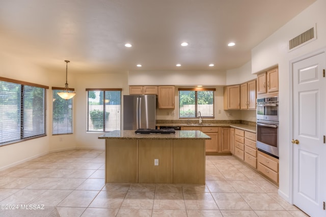 kitchen featuring a kitchen island, sink, decorative light fixtures, appliances with stainless steel finishes, and light stone counters