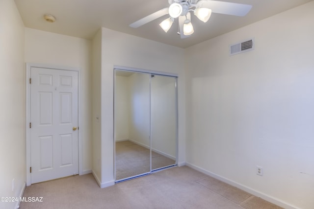 unfurnished bedroom with light carpet, a closet, and ceiling fan