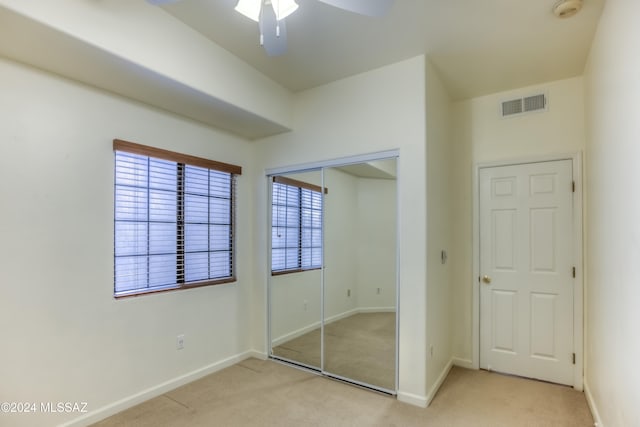 unfurnished bedroom with a closet, ceiling fan, multiple windows, and light colored carpet