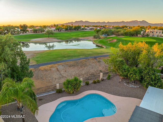 pool at dusk with a yard and a water and mountain view