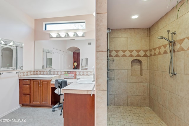 bathroom with vanity, a tile shower, tile patterned floors, and decorative backsplash