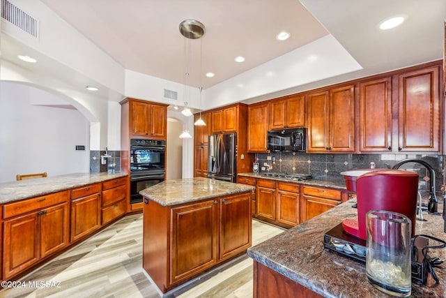 kitchen with decorative light fixtures, black appliances, dark stone counters, a center island, and kitchen peninsula