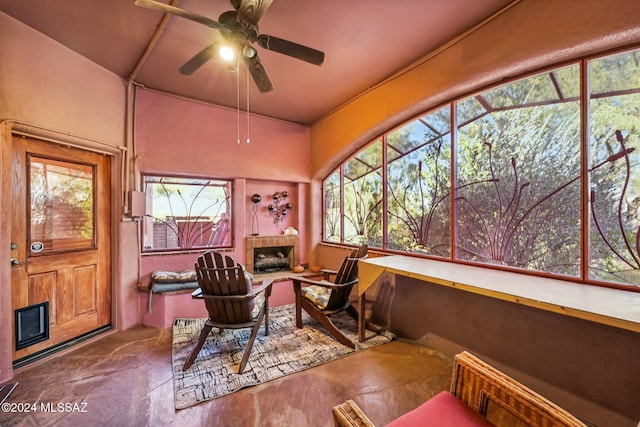 interior space featuring a tiled fireplace and ceiling fan