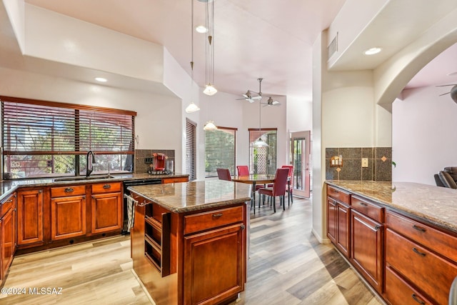 kitchen with pendant lighting, dishwasher, backsplash, sink, and light wood-type flooring