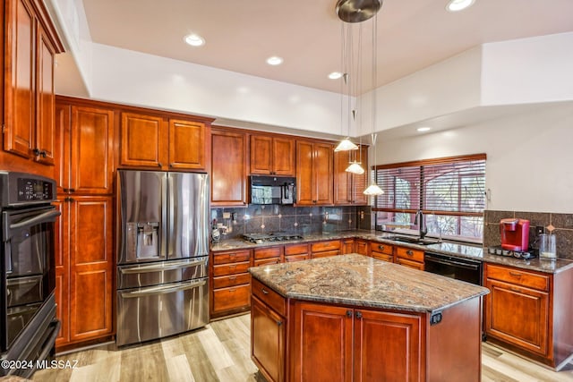 kitchen with stone counters, pendant lighting, sink, a center island, and black appliances