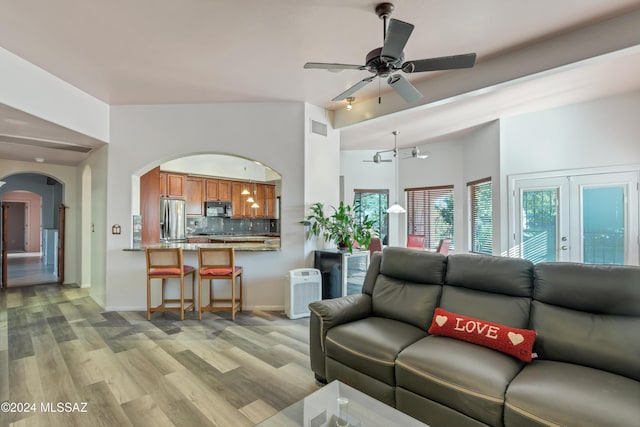 living room featuring ceiling fan, vaulted ceiling, and light hardwood / wood-style flooring