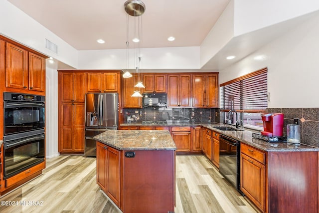 kitchen featuring sink, decorative light fixtures, a center island, dark stone countertops, and black appliances