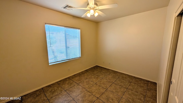 spare room featuring dark tile patterned flooring and ceiling fan