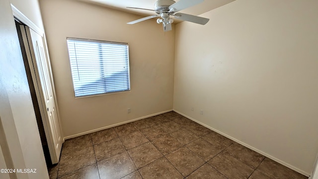 spare room with dark tile patterned floors and ceiling fan