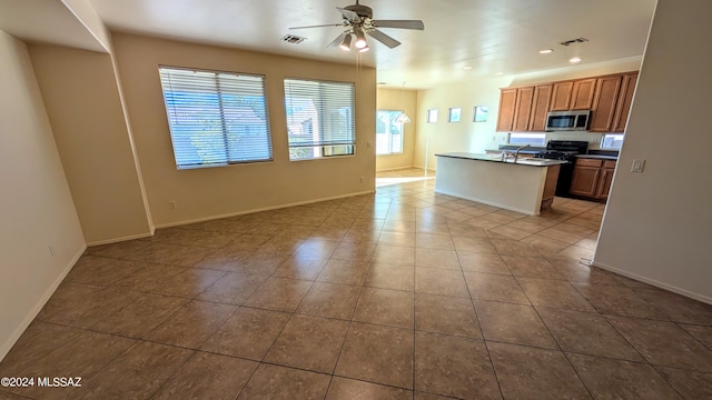 kitchen with ceiling fan, plenty of natural light, and a center island with sink