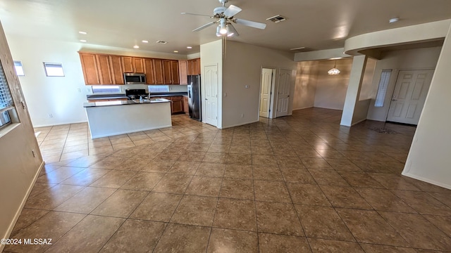 kitchen with ceiling fan, stainless steel appliances, tile patterned floors, and an island with sink