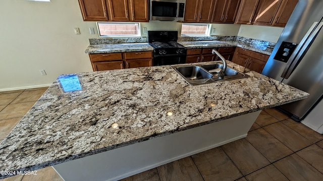 kitchen with sink, light stone countertops, stainless steel appliances, and a breakfast bar