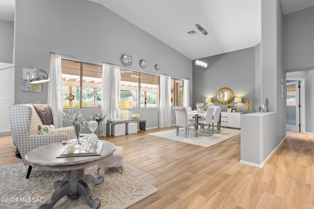 sitting room featuring light hardwood / wood-style floors, high vaulted ceiling, and a notable chandelier