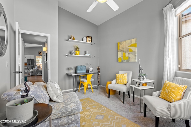 sitting room with ceiling fan, lofted ceiling, and carpet