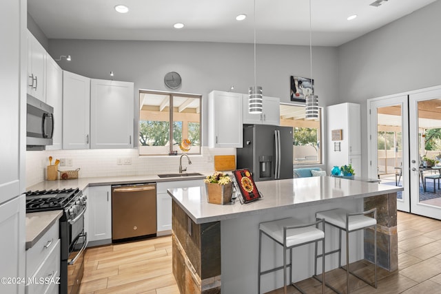 kitchen featuring appliances with stainless steel finishes, sink, a center island, and white cabinets