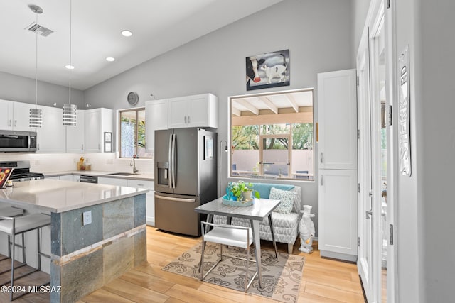 kitchen featuring light hardwood / wood-style flooring, appliances with stainless steel finishes, vaulted ceiling, and white cabinetry