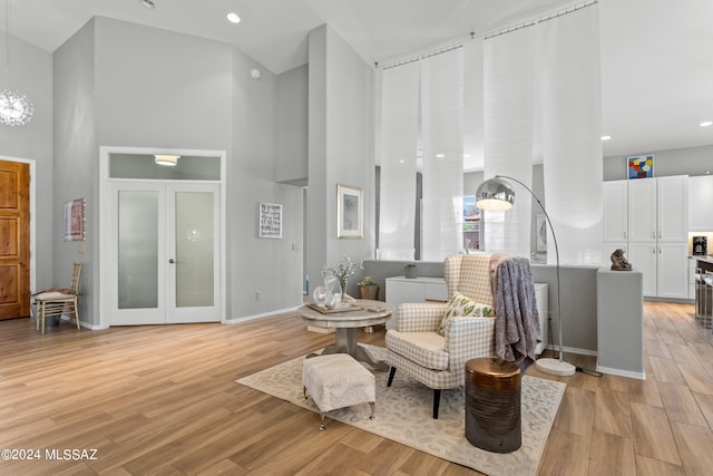 living area with light wood-type flooring and a towering ceiling