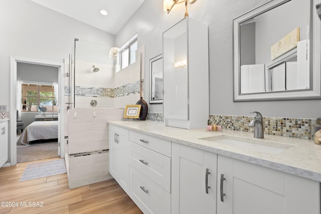 bathroom featuring wood-type flooring, a shower, vanity, and decorative backsplash