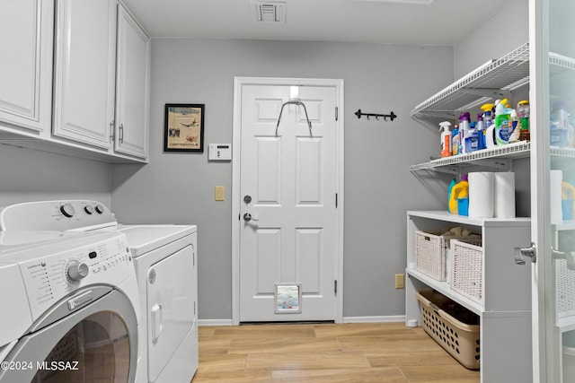 washroom with cabinets, light hardwood / wood-style floors, and washing machine and dryer