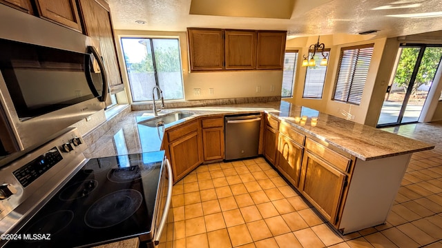 kitchen featuring kitchen peninsula, appliances with stainless steel finishes, a textured ceiling, and plenty of natural light