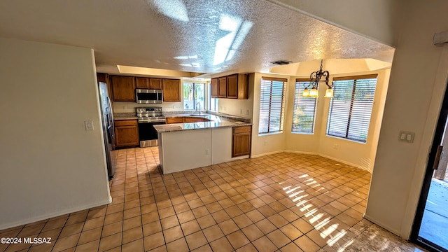 kitchen featuring light tile patterned flooring, pendant lighting, stainless steel appliances, and a textured ceiling